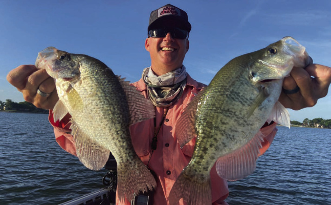 Cedar Creek Lake guide Chris Webb with two of many crappie landed this past week. Crappie are on a very dependable summer bite, holding tight to submerged structure but the bite is soft and proper technique is key to getting the hook set. Photo by Luke Clayton