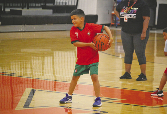 Monitor Photo/Russell Slaton Ethan Murillo shares a smile while learning basketball skills under the tutelage of LaCedra Miller (partial, in background) at the July 6 basketball skills camp.