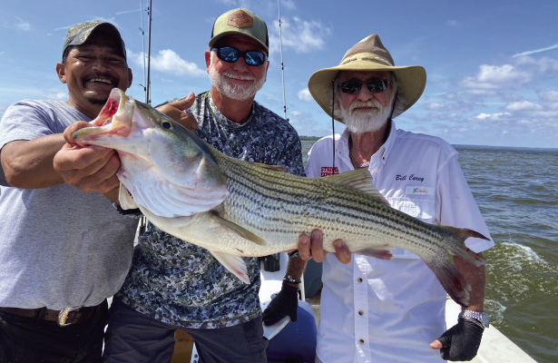 Jeff Rice, middle, shows off the big striper of the day landed with guide Lil’ Dave, left, and Bill Carey. Photo by Luke Clayton