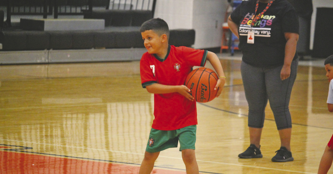 Monitor Photo/Russell Slaton Ethan Murillo shares a smile while learning basketball skills under the tutelage of LaCedra Miller (partial, in background) at the July 6 basketball skills camp.